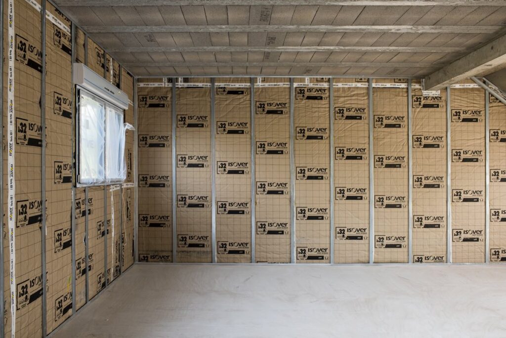 Isolation thermique intérieure (ITI) – pose de laine minérale entre montants métalliques sur mur intérieur maison en Isère